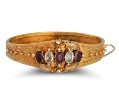 AN ANTIQUE GARNET AND WHITE GEMSTONE BANGLE, in yellow gold, Etruscan style decoration ** testing as 54% gold