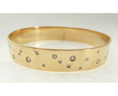 DIAMOND SET GOLD METAL BANGLE, the elliptical shaped bangle randomly flush set with 18 round brilliant cut diamonds, 0.08ct-0