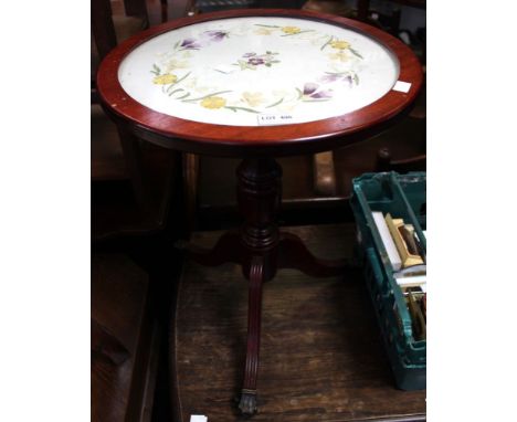 A low tripod wine table with claw caster feet and silk upholstered top beneath glass