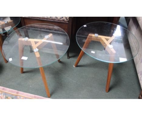 A pair of modern wooden tripod side tables with circular glass tops