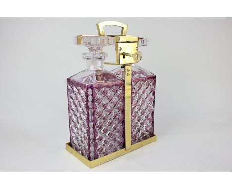 A two-bottle purple and clear glass spirit decanter tantalus with gilt metal frame and lock with key