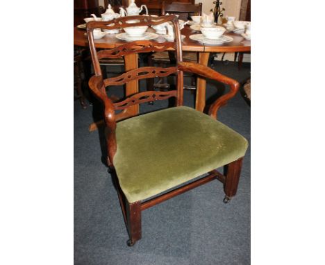 A Chippendale style mahogany carver dining chair with pierced ladder back, curved arms, and green velvet upholstered seat, on