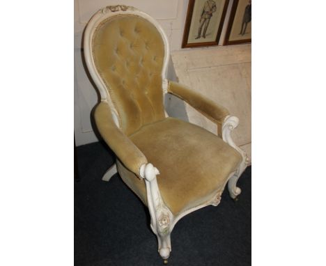 A white painted balloon back armchair with button upholstered back, open padded arms, on floral carved supports and cabriole 