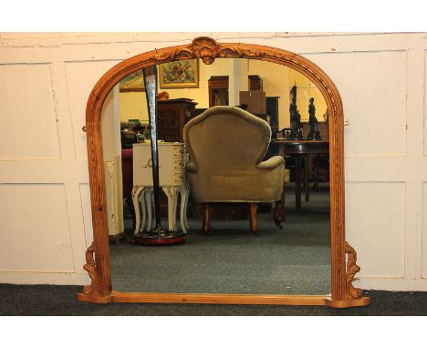 A pine overmantel mirror in arched frame with carved shell surmount, 134cm wide, 117cm high