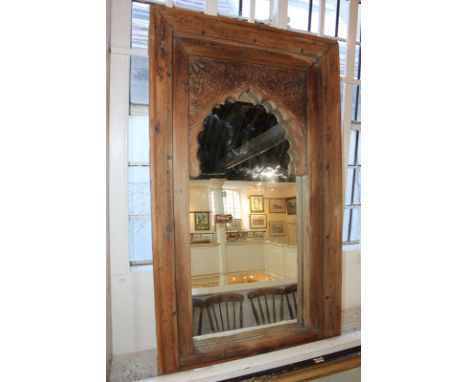 An Indian carved wood rectangular wall mirror, possibly converted from a window, with arch shaped mount, carved with flowers 