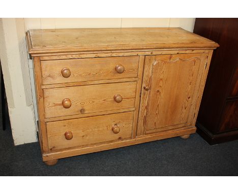 A pine cabinet with rectangular top, three drawers and panel door enclosing shelf, on bun feet, 120.5cm