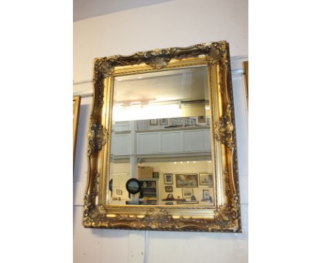 A reproduction gilt painted rectangular wall mirror with scroll and foliate decoration, bevelled plate size 60cm by 45cm