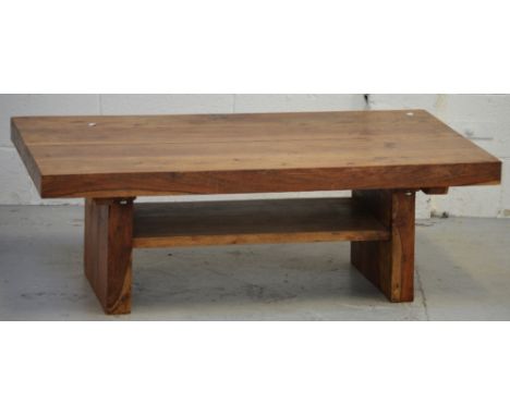 A contemporary hardwood coffee table with lower shelf on block supports, length 117cm.