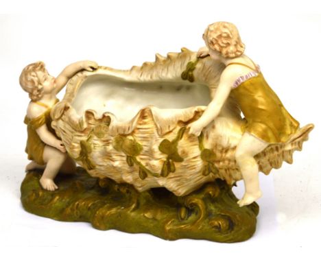 A Royal Vienna Ernst Wahliss ceramic centrepiece, a bowl in the form of a shell on which two children are playing, ivory and 