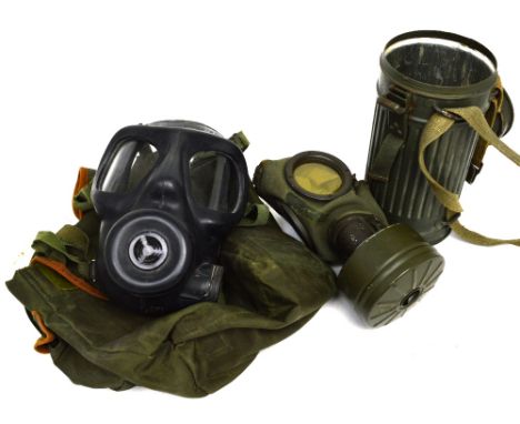 A mid-20th century gas mask in tin canister, together with a later rubber gas mask in canvas case, each with elasticated canv