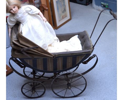 A Victorian dolls' pram with curved wooden body, leather interior and hood, on metal wheels, small enamel plaque to the front