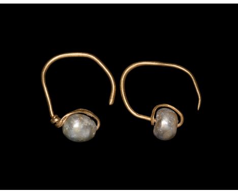 1st-3rd century AD. A matched pair of silver-gilt earrings, each a round-section hoop with one end coiled about the shank and
