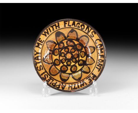 Dated 1963 AD. A glazed and slip decorated ceramic dish with concentric rings to the centre, petals and band of text to the r