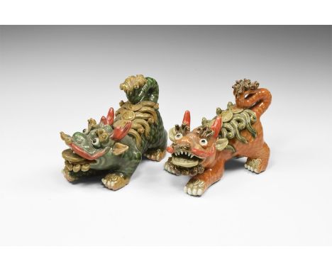 20th century AD. A pair of ceramic Foo Dogs, each crouching, front paws extended forward; mouth open baring teeth and coin in