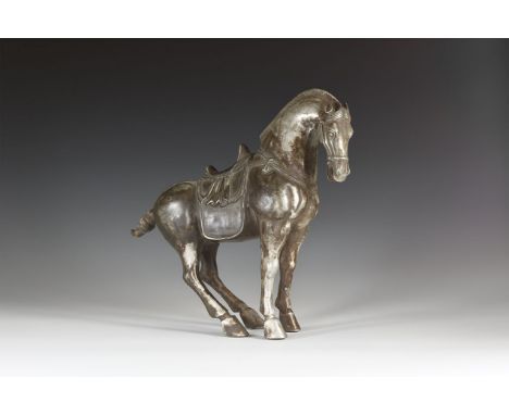 An undated archaistic silver coloured metal Tang style horse with head turned to the right, mouth open and ears back; harness