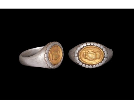 An undated archaistic silver finger ring with D-section shank, expanding shoulders, pelleted border to the bezel, inset gold 