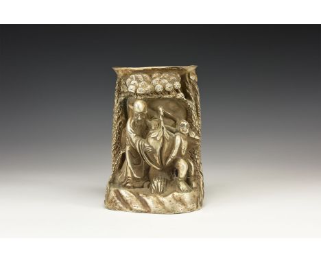 An undated archaistic silver coloured metal brush pot in the form of a mountain landscape with trees framing a central recess