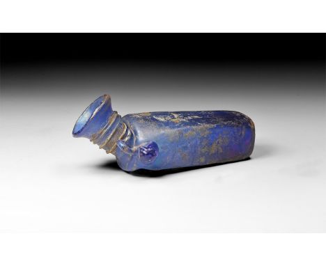 An undated archaistic blue glass square-section flask with pontil base, trumpet-shaped mouth with rolled rim, applied trail t