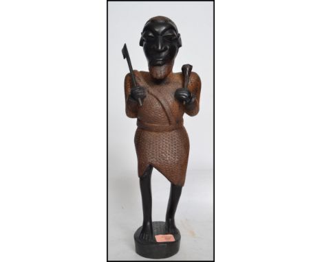 A 20th century large Aboriginal Tribal carving figurine of a warrior holding an axe and spear raised on a wooden plinth base.