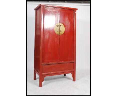 A Chinese large 20th century red lacquered marriage cupboard wardrobe. The large cabinet with turned legs having panel doors 