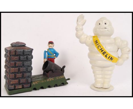 A collection of 2x 20th century vintage style cast iron money boxes to include; Michelin Man bank (approx 21cm tall) & 'Artil