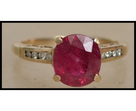 A hallmarked 9ct gold ring set with a central ruby with diamond accent shoulders. Hallmarked Birmingham. Size Q. Total Weight