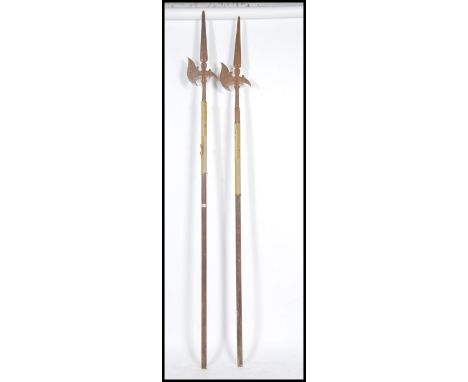 A pair of decorative 20th century large Poleaxes, each on hexagonal wooden poles with cast metal axe heads