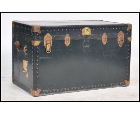 A large vintage metal bound steamer travelling trunk, with locking mechanism, hinged lid and vacant interior in a dark green 