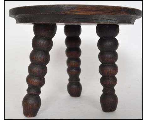 An unusual early 20th century oak milking stool with turned bobbin legs