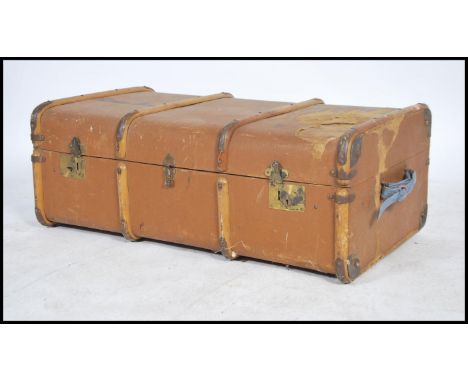 A vintage 20th century canvas and wooden bound steamer trunk having three lock catches to front with hinged lid opening to re