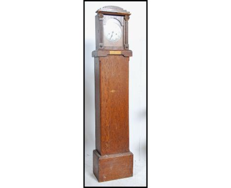 An early 20th century oak cased mantel clock with an eight day movement set on a purpose built plinth and bearing a brass pla