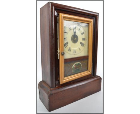 An early 20th century American gingerbread clock set in a rosewood case having a Roman numeral chapter ring with faceted hand