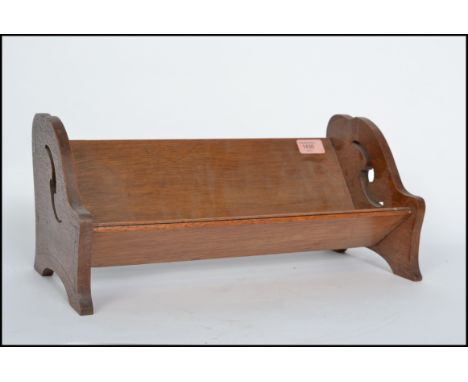 A 1930's Arts and Craft oak book trough of usual form having fret pierced design to the sides. 19cms high x 41cms wide x 20cm