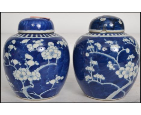 A pair of Oriental 19th century Kangxi ceramic blue and white ginger jars with lids decorated in a prunus pattern with double