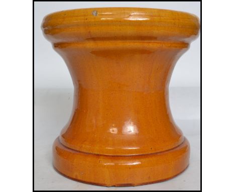 A vintage ceramic terracotta planter plant stand having a tapering base with a yellow glaze finish. 