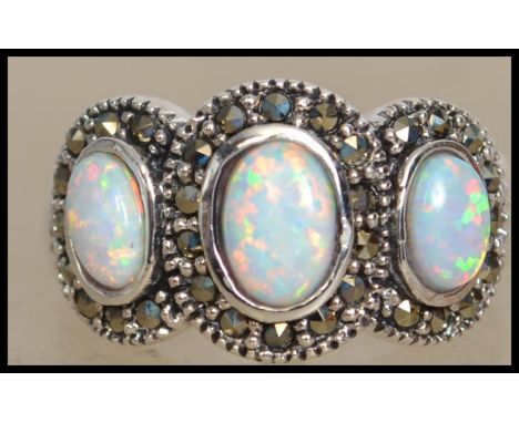 A silver ladies Art Deco style 3 stone opal ring. Each stone of cabochon form having marcasite concentric halo's. Weight 6.1g