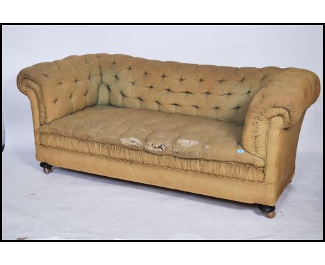 A 19th century Victorian Chesterfield sofa raised on bun feet having a green fabric button backed seat and back rest, barrel 