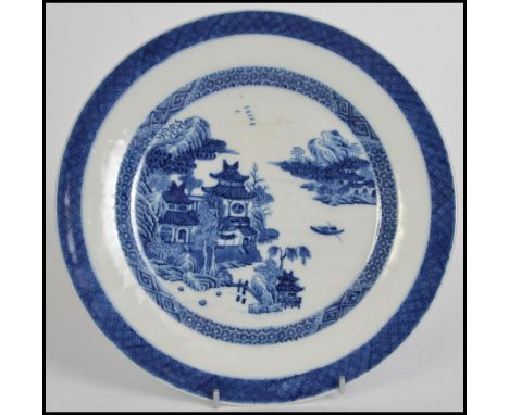 An 18th / 19th century Chinese blue and white ceramic plate in the willow pattern with scenes of fisherman, pagoda, lake etc.