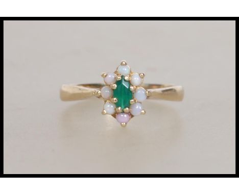 A hallmarked 9ct gold ring set with  a central green stone surrounded by an opal halo. Hallmarked Birmingham. Weight 3.1g.  S