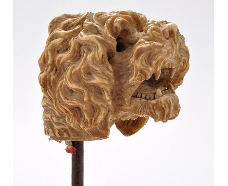 A late 19th Century carved ivory cane finial, modelled as a dog bearing its teeth, fitted glass eyes (one missing), on metal 