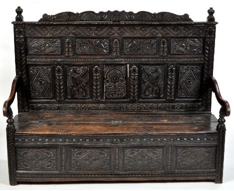 A 17th Century carved oak settle, the back with reeded finials above panels of foliate scrolls, dragons, lozenge motifs and i