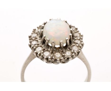 An opal and diamond cluster ring, the oval opal measuring 8.6 x 7mm, claw set surrounded by fourteen brilliant cut diamonds, 