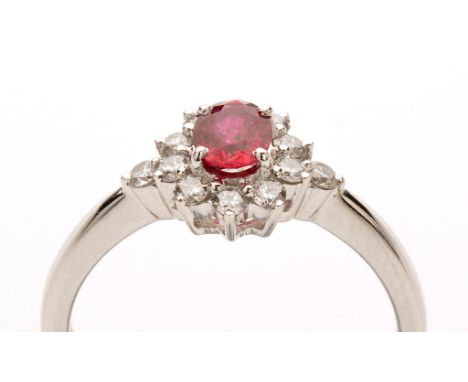 A ruby and diamond cluster ring, the central oval facet cut ruby four claw set surrounded by brilliant cut diamonds within a 
