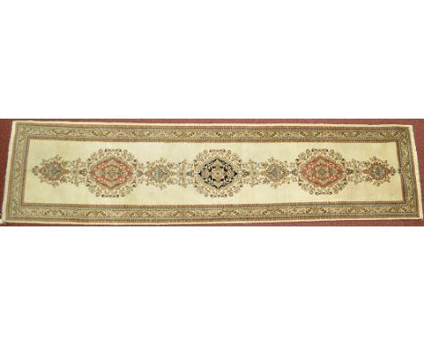 A Tabriz runner, the ivory field decorated with floral medallions and foliate border, 119 x 28in. (302 x 71cms).