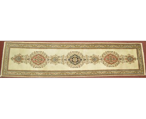 A Tabriz runner, the ivory field decorated with floral medallions and foliate border, 119 x 28in. (302 x 71cms).