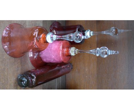 Three Victorian cranberry glass bells with clear handles, one a/f and a Victorian cranberry glass rolling pin