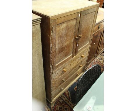 An early 20th Century limed oak bedroom cabinet with two doors above three drawers on splayed bracket feet in the manner of  