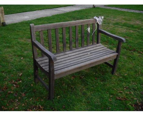 A modern carved teak bench seat of slatted construction