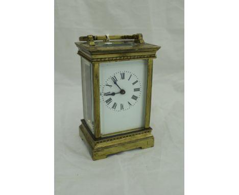 A lacquered brass cased carriage clock with white enamel dial and Roman numerals