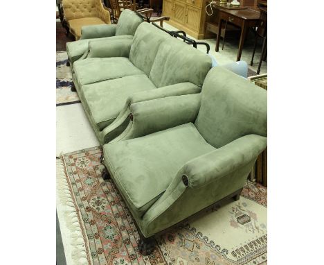 A Victorian three piece suite comprising two seat sofa and two armchairs, the plain backs above scroll arms with carved wood 